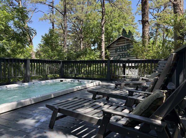 A hot tub area with lounge chairs and a wooden deck.