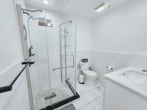 Un baño moderno con ducha de vidrio, inodoro blanco y lavabo de mármol.