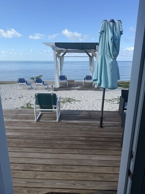 A wooden deck with beach chairs and a covered area with umbrellas. - Stylish 1-Bedroom Condo with Modern Comforts in the Heart of Nassau (Nassau)