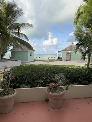 Blick auf einen Strand mit einer Laube, Liegestühlen und einem kleinen Gebäude.