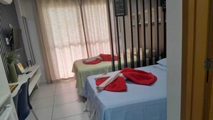 Une chambre d’hôtel avec deux lits, un bureau avec un ordinateur et une fenêtre avec des rideaux.