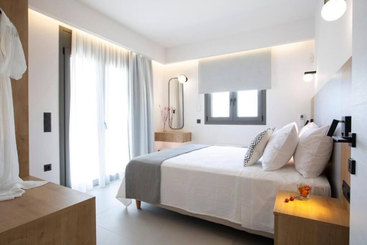 A modern bedroom with a large bed, bedside tables, a mirror, and a window.