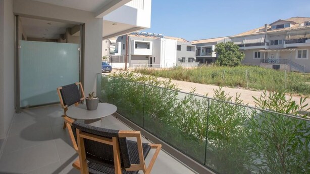 Ein Balkon mit Tisch und Stühlen, mit Blick auf ein Wohngebiet mit Häusern und Grünflächen.
