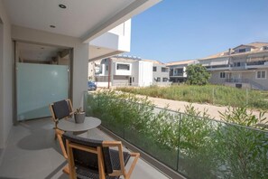 A balcony with a table and chairs, overlooking a residential area with houses and greenery. - Achillion Suites (Lefkada)