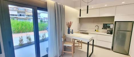 Een moderne keuken met een eethoek, grote ramen en uitzicht op groen.