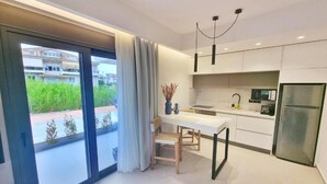 Una cocina moderna con comedor, ventanas amplias y vistas al exterior con vegetación.