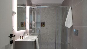Ein modernes Badezimmer mit einer begehbaren Glasdusche, einem weißen Waschbecken und einer Toilette.