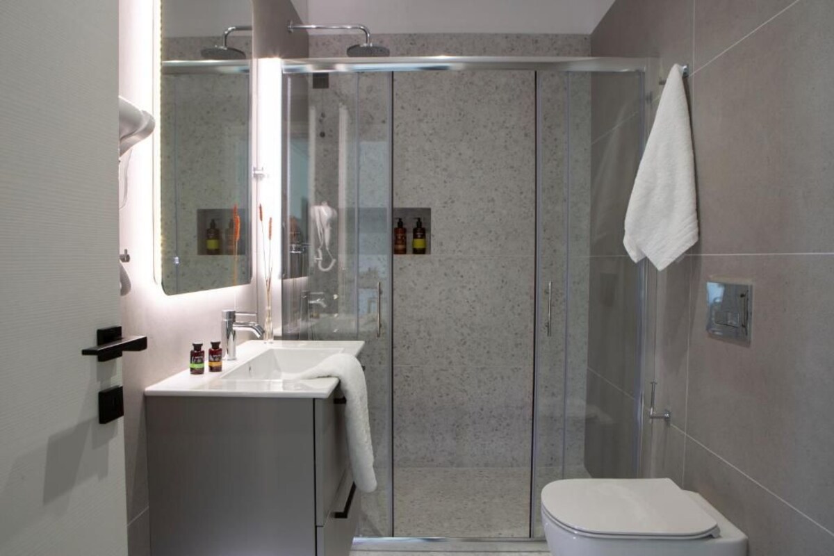 Ein modernes Badezimmer mit einer begehbaren Glasdusche, einem weißen Waschbecken und einer Toilette.