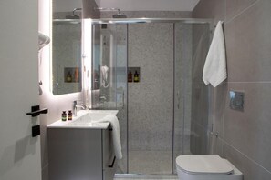 Une salle de bain moderne avec une douche à parois de verre, un lavabo blanc et des toilettes.