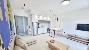 A modern living room with a sofa, a coffee table, and a dining area with a table and chairs. - Achillion Suites (Lefkada)