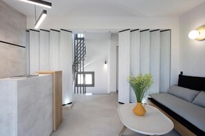 Egy modern belső tér, amelyben található egy recepciós pult, egy lépcsőház, valamint egy ülősarok, kanapéval és asztallal.