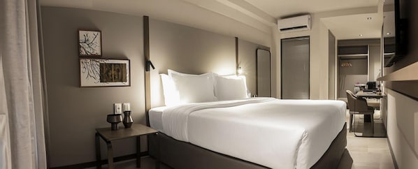 Een moderne hotelkamer met een groot bed, nachtkastje en bureau met stoel.