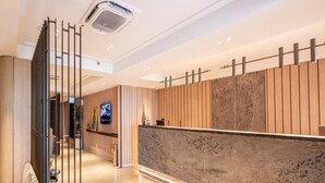 Een hotel receptie met een receptiebalie, een televisie en een modern interieur.