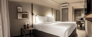 Een moderne hotelkamer met een groot bed, nachtkastje en bureau met stoel.
