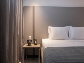 Una habitació d'hotel amb llit, una vetusta, una làmpada i una cortina.