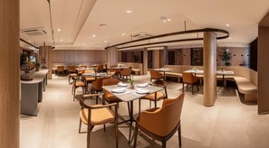 A modern restaurant with round tables and orange chairs, featuring a curved ceiling and wooden accents.