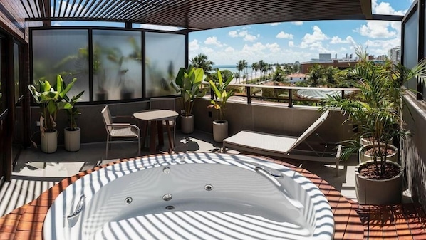 Een terras op het dak met een jacuzzi, een zitgedeelte en potplanten.