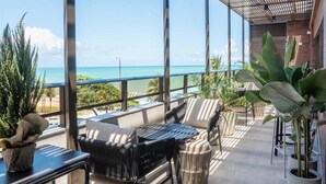 Een balkon met uitzicht op de oceaan, voorzien van rieten stoelen en een klein tafeltje.