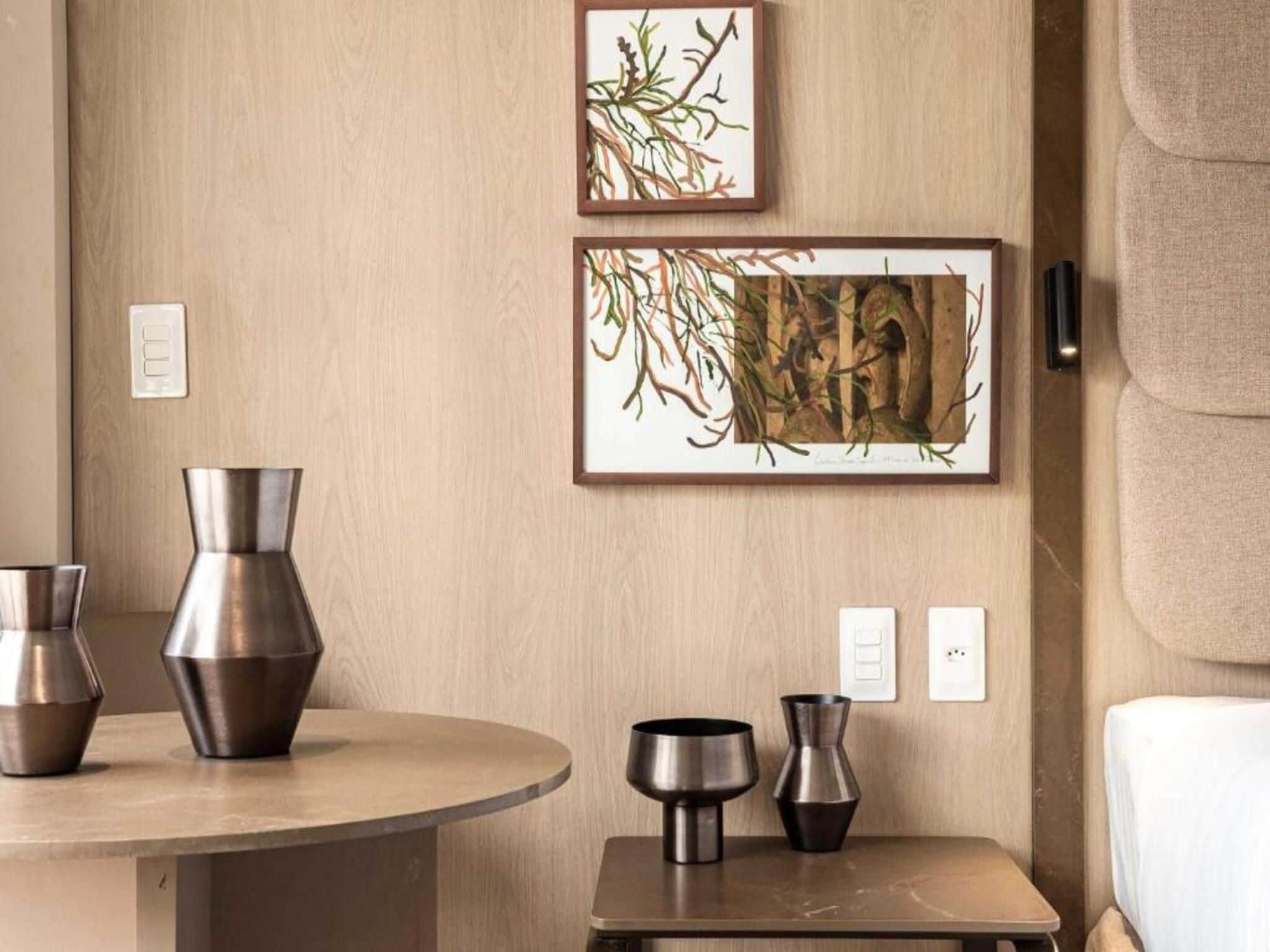 A room with a round table, two vases, and two framed artworks on the wall.
