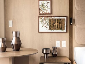 A room with a round table, two vases, and two framed artworks on the wall.