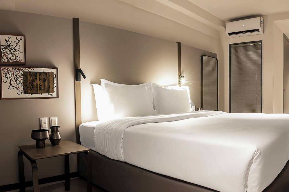 Ein modernes Hotelzimmer mit einem großen Bett, einem Nachttisch und einem Schreibtisch mit Stuhl.