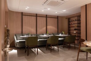 Un comedor moderno con sofá y sillas, una mesa pequeña y un estante con botellas.