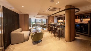 A modern bar area with seating, a bar counter, and a refrigerator stocked with beverages.