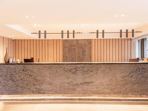 Un espace d’accueil agrémenté d’un mur en panneaux de bois, d’un comptoir en marbre et d’un luminaire moderne.