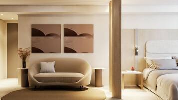 A modern hotel room with a sofa, a bed, a round rug, and two wall-mounted artworks.