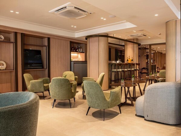 Un espace lounge moderne comprenant des sièges, un bar et un téléviseur.