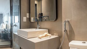 Un baño moderno con un lavamanos blanco, un espejo y una ducha.