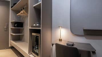 A modern room with a built-in closet, a desk with a lamp, and a flat-screen TV mounted on the wall.