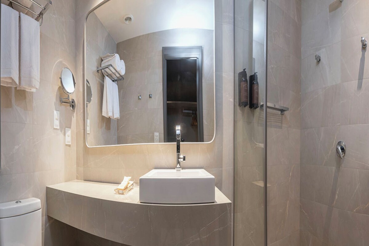 Une salle de bain moderne avec un meuble-lavabo aux lignes courbes, un grand miroir et une douche à parois de verre.