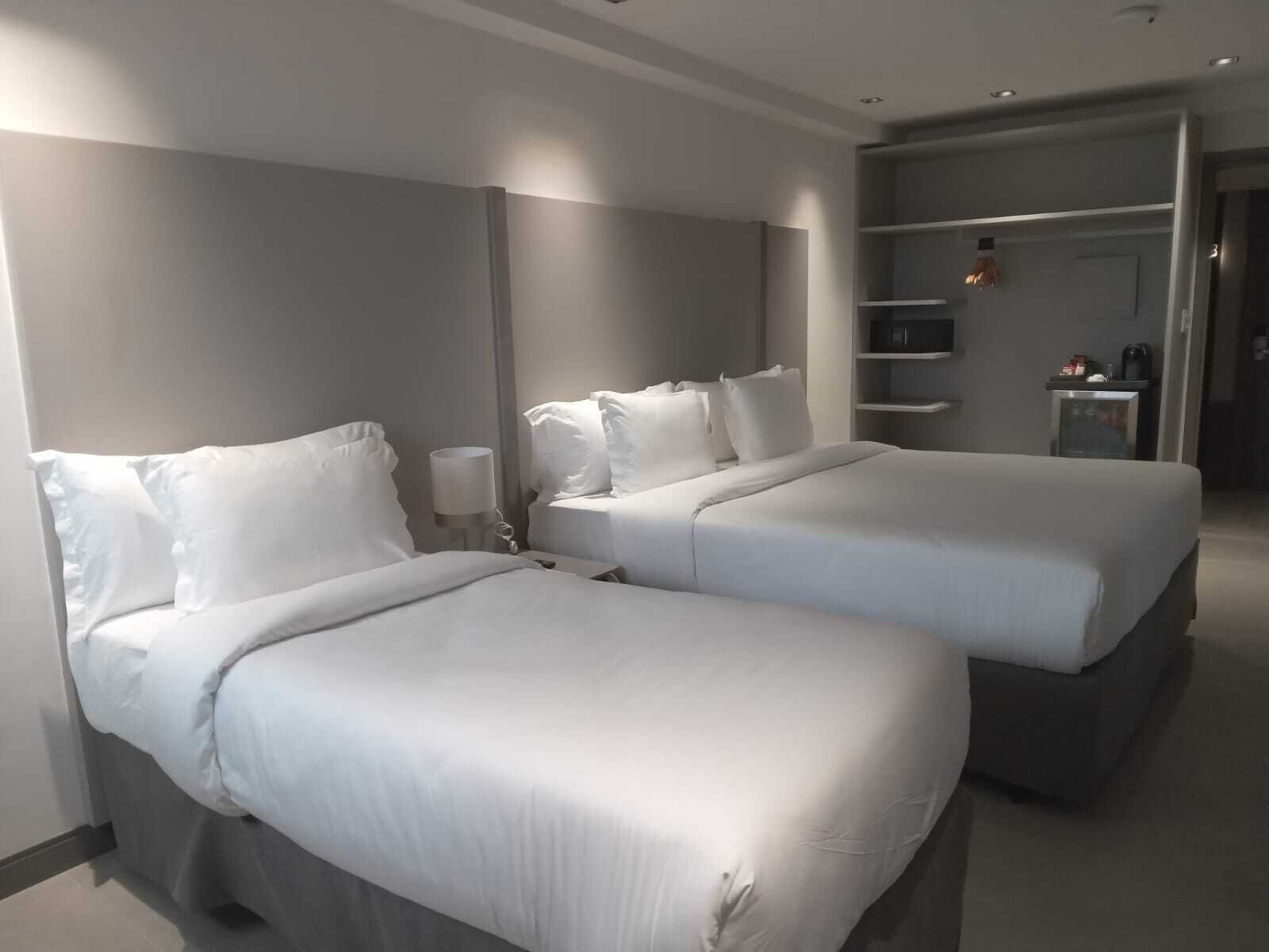 Ein Hotelzimmer mit zwei Betten, einem Nachttisch mit Lampe und einem Kleiderschrank.