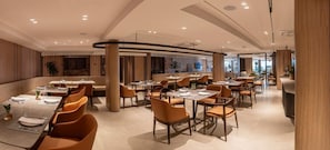 Un restaurant moderne doté de nombreuses tables et chaises, et présentant un design épuré et contemporain.