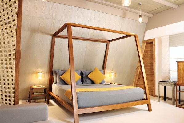 Una cama con dosel de madera, dos mesitas de noche y un taburete pequeño.