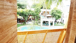 Zona de piscina con cubierta de madera, rodeada de vegetación y una zona de bar.