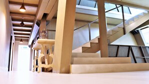 Un interior moderno con una escalera, vigas de madera e iluminación colgante.