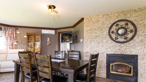 Un comedor con pared de piedra, chimenea y televisor montado en la pared.