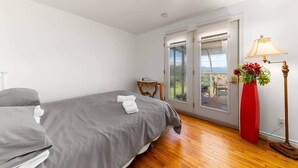 Un dormitorio con una cama, una mesita de noche, una lámpara y vistas a través de una puerta de cristal.