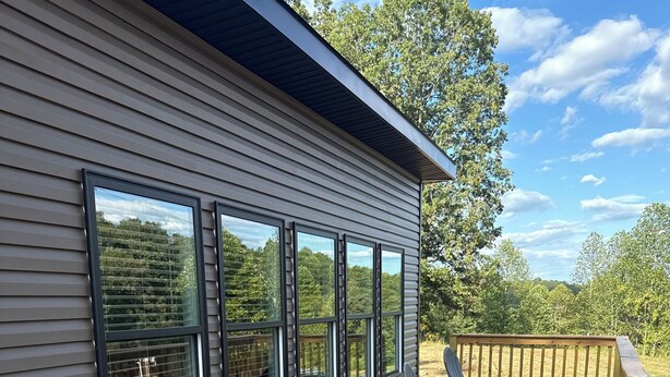 A deck with outdoor furniture and a view of a house with large windows.