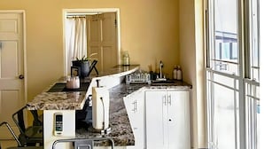 Een keuken met een granieten aanrecht, een ingebouwde oven, een koffiezetapparaat en een raam met uitzicht.