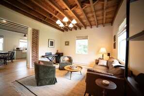 A spacious living area with a high ceiling, a fireplace, a dining table, and a cozy seating arrangement.
