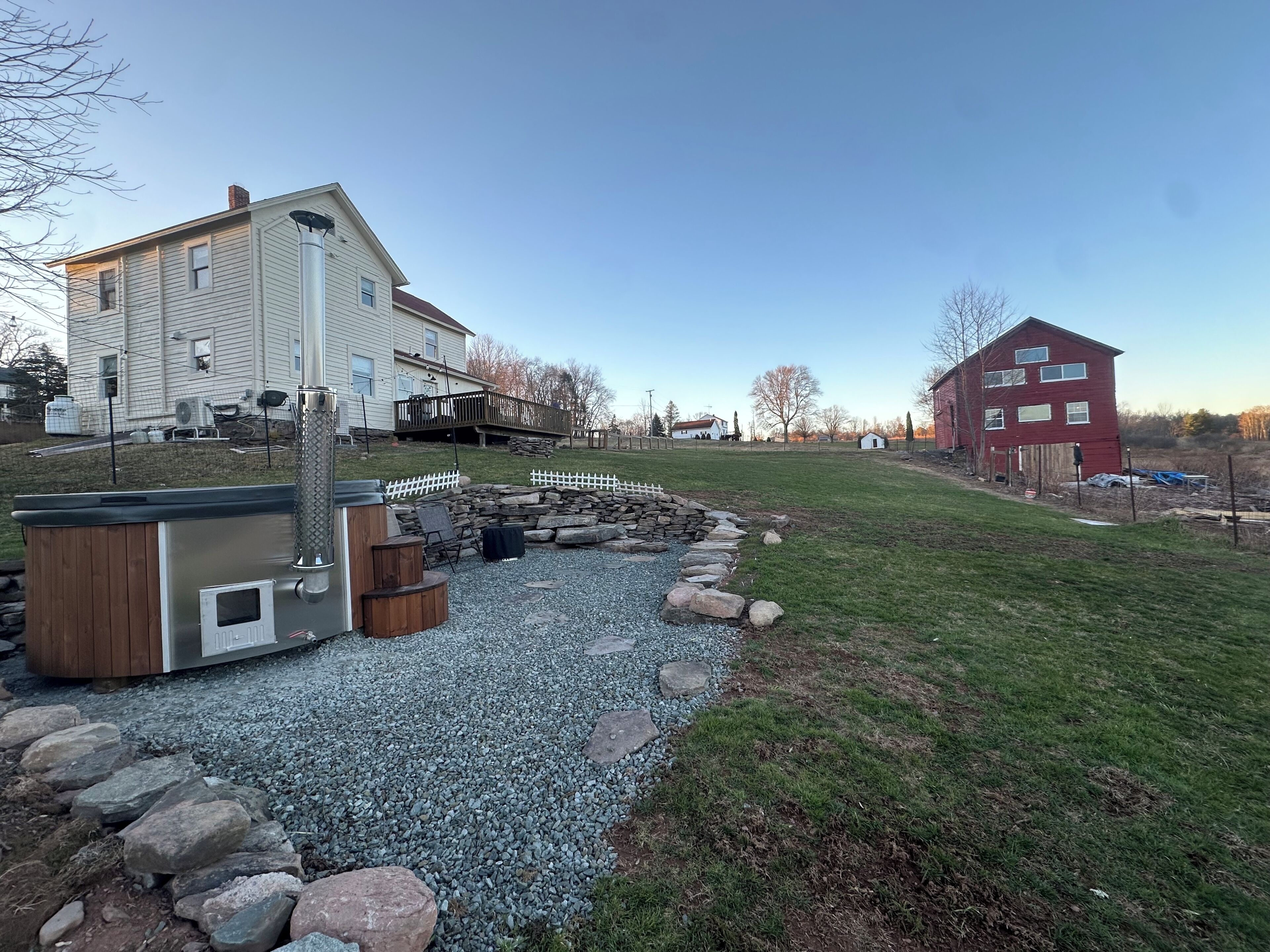 A residential area with a house, a hot tub, and a stone fire pit.