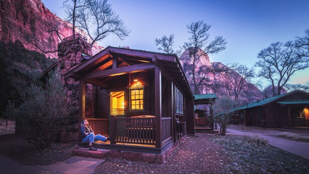 Une cabane en bois dotée d’un porche, située dans un paysage montagneux.