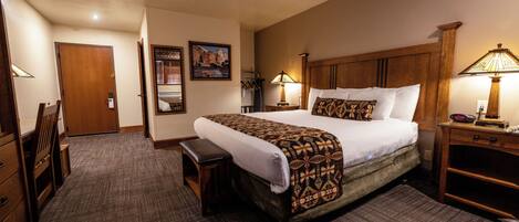 A hotel room with a large bed, bedside tables, a desk, and a chair.