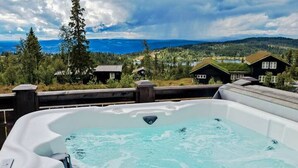 A hot tub with a view of a mountainous landscape and houses.