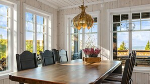 A dining room with a wooden table, chairs, and a hanging light fixture.