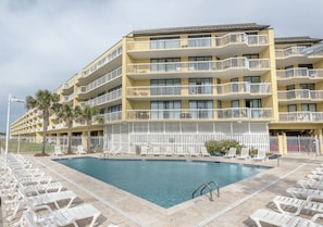 Un hotel de varios pisos con balcones, piscina y tumbonas.