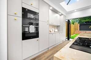 A modern kitchen with integrated appliances, a large window, and a view of the outdoors.